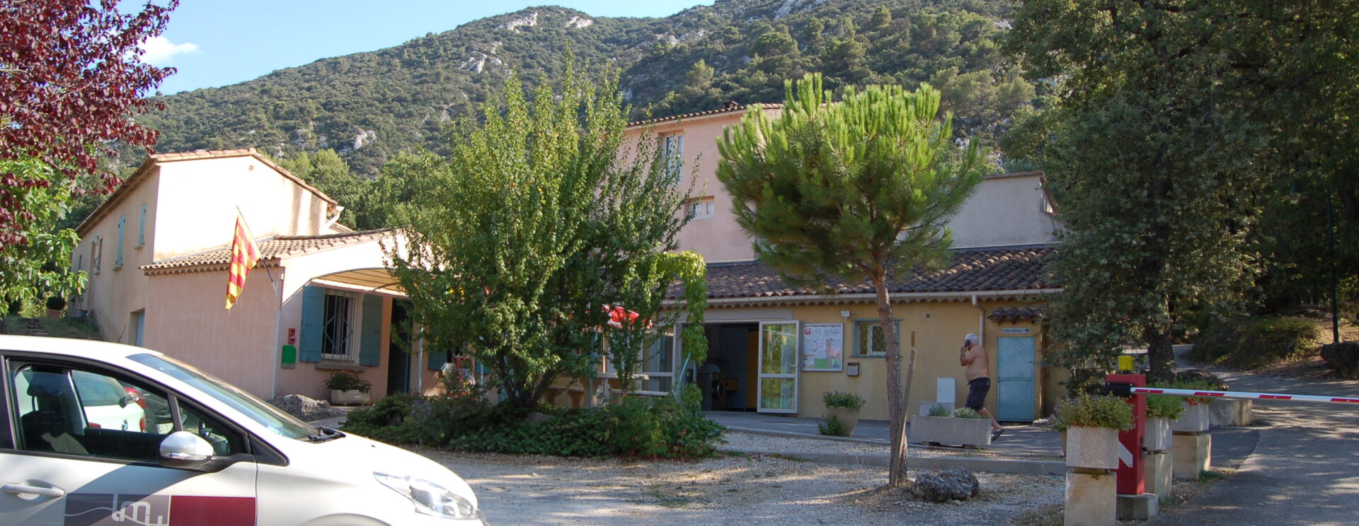 Vue de l'entrée du camping Les Royères du Prieuré de Maubec (accueil et sanitaire) avec en fond, le massif du petit Luberon.