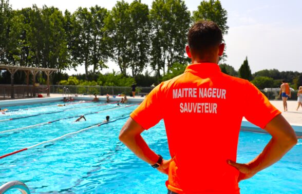 Une maitre nageur sauveteur de dos, face au bassin en sureveillance